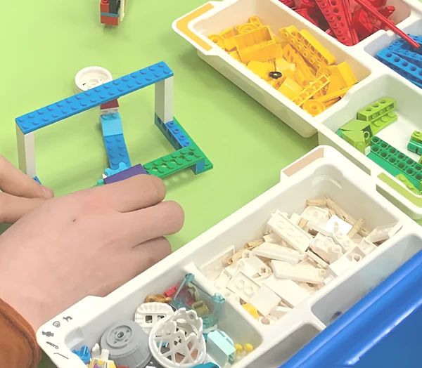 Ребёнок изучает LEGO-конструирование. Он строит модель из LEGO-деталей.