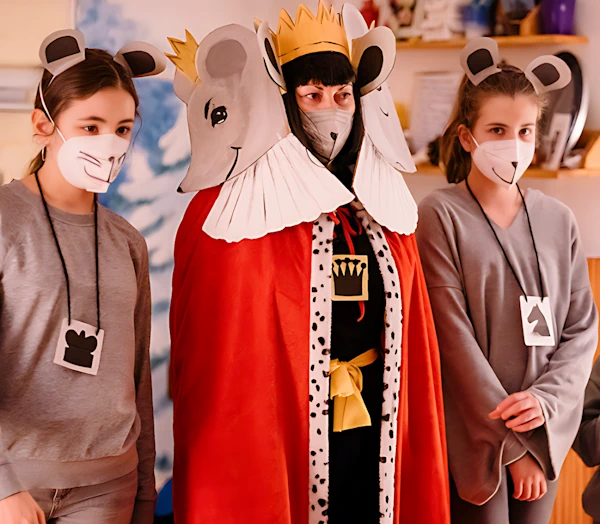 Преподаватель в костюме короля мышей и двое подростков в костюмах мышей показывают сказку.